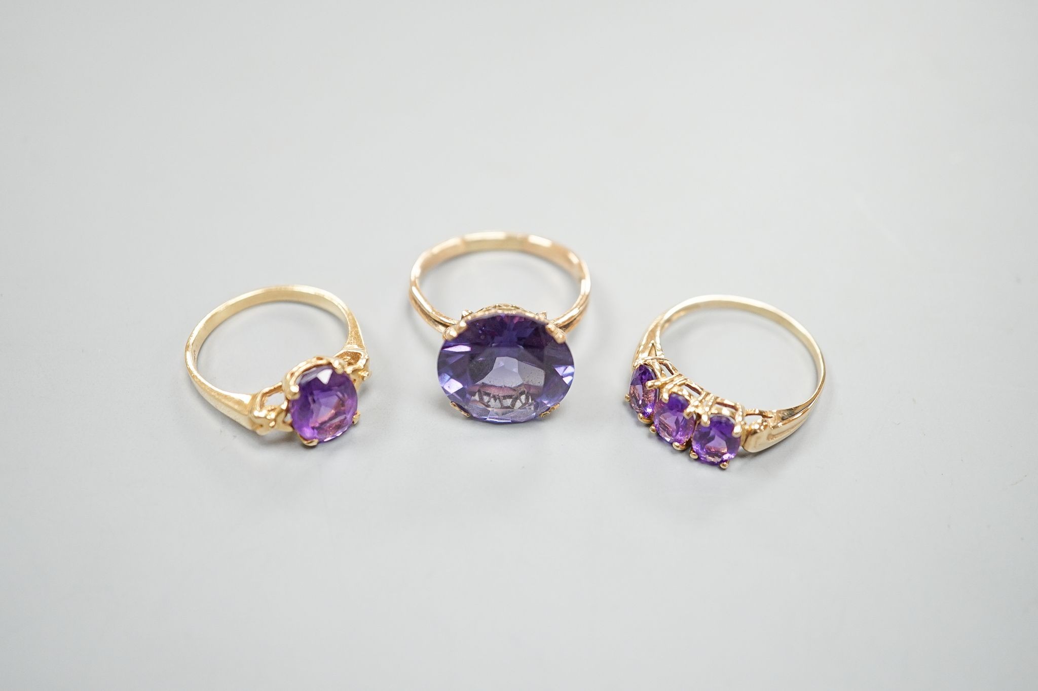 Two modern 14k yellow metal and gem set rings, including amethyst, size N, gross weight 7.4 grams and a similar 10k and three stone amethyst ring, size Q/R, gross 2.3 grams.